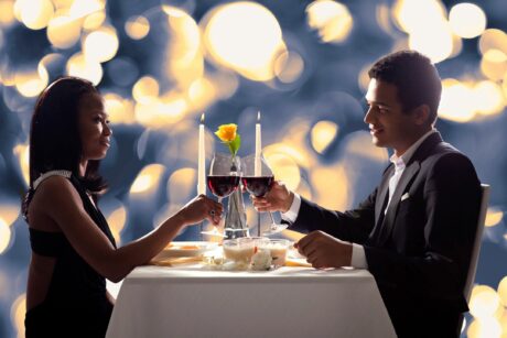 couple toasting at dinner table with glasses of red wine