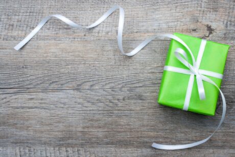 gift wrapped in lime green paper and white ribbon sitting on barn board table