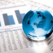 glass globe of world sitting on a business graph information sheet