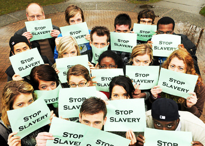 large group of men and women holding posters saying stop slavery