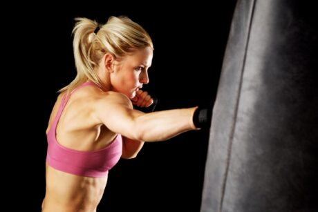 woman punching a bag wearing a rose colored sports bra