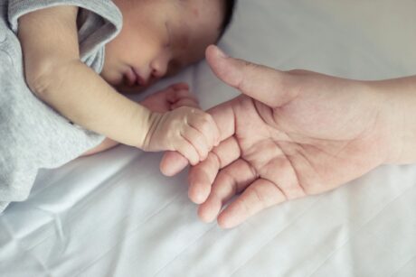 toddler baby holding parent's finger while falling to sleep