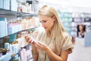 blonde woman reading labels to research before she purchases new product