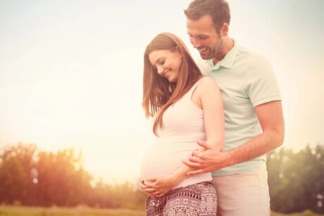 couple holding onto tummy of pregnant woman