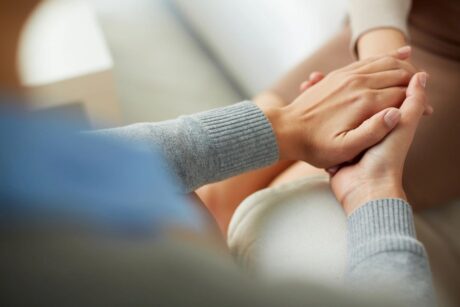 female psychiatrist holding female patient hand showing comfort