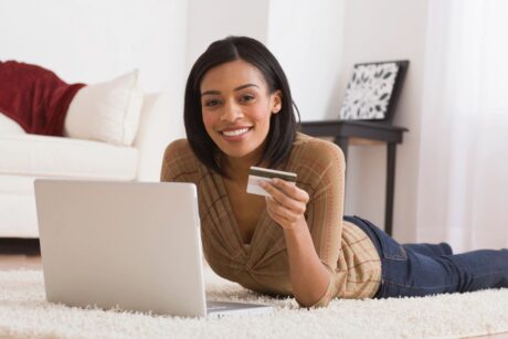 woman with laptop holding credit card smiling