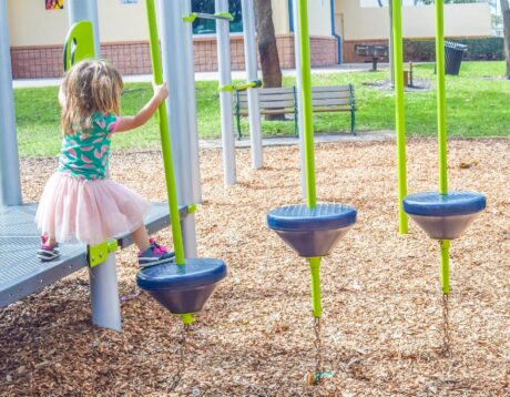 little girl playing outdoors on playground equipment