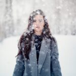woman in snow storm wearing grey stylish winter coat