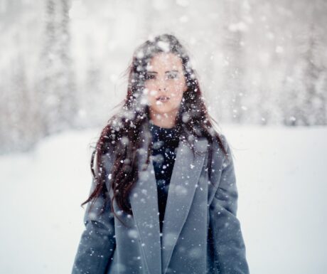 woman in snow storm wearing grey stylish winter coat 